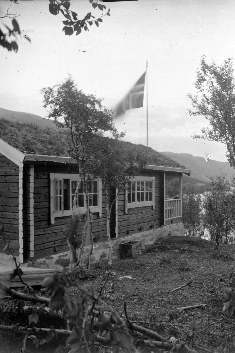 Hytta til Kristian Holst i Tømmeråsen. Flagg i bakgrunnen.