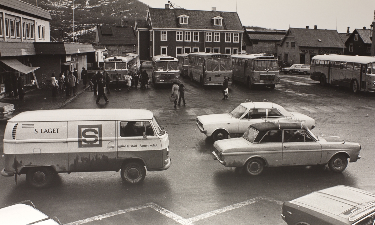 Busser og mennesker på rutebilstasjonen i sentrum, fotografert i 1973 eller 1974. Biltrafikk i forgrunnen.