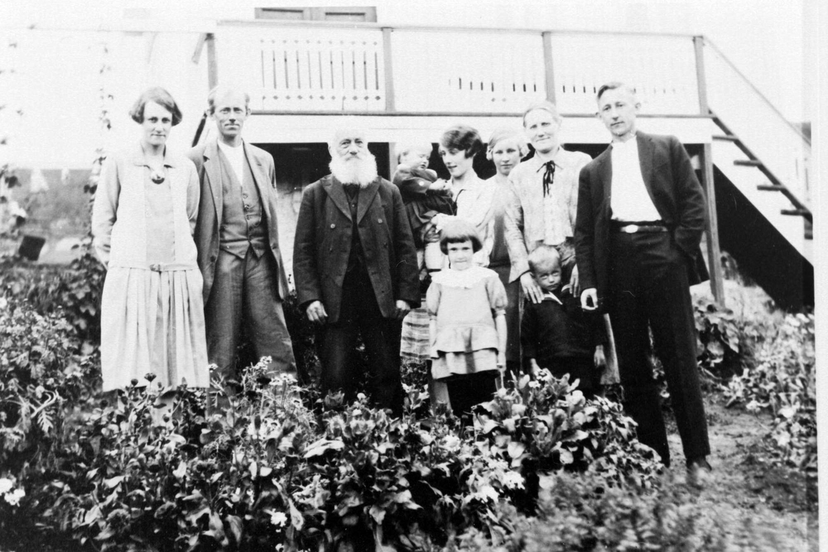 Gruppebilde av Lars Johnsen med familie, tatt i hagen foran et hus.