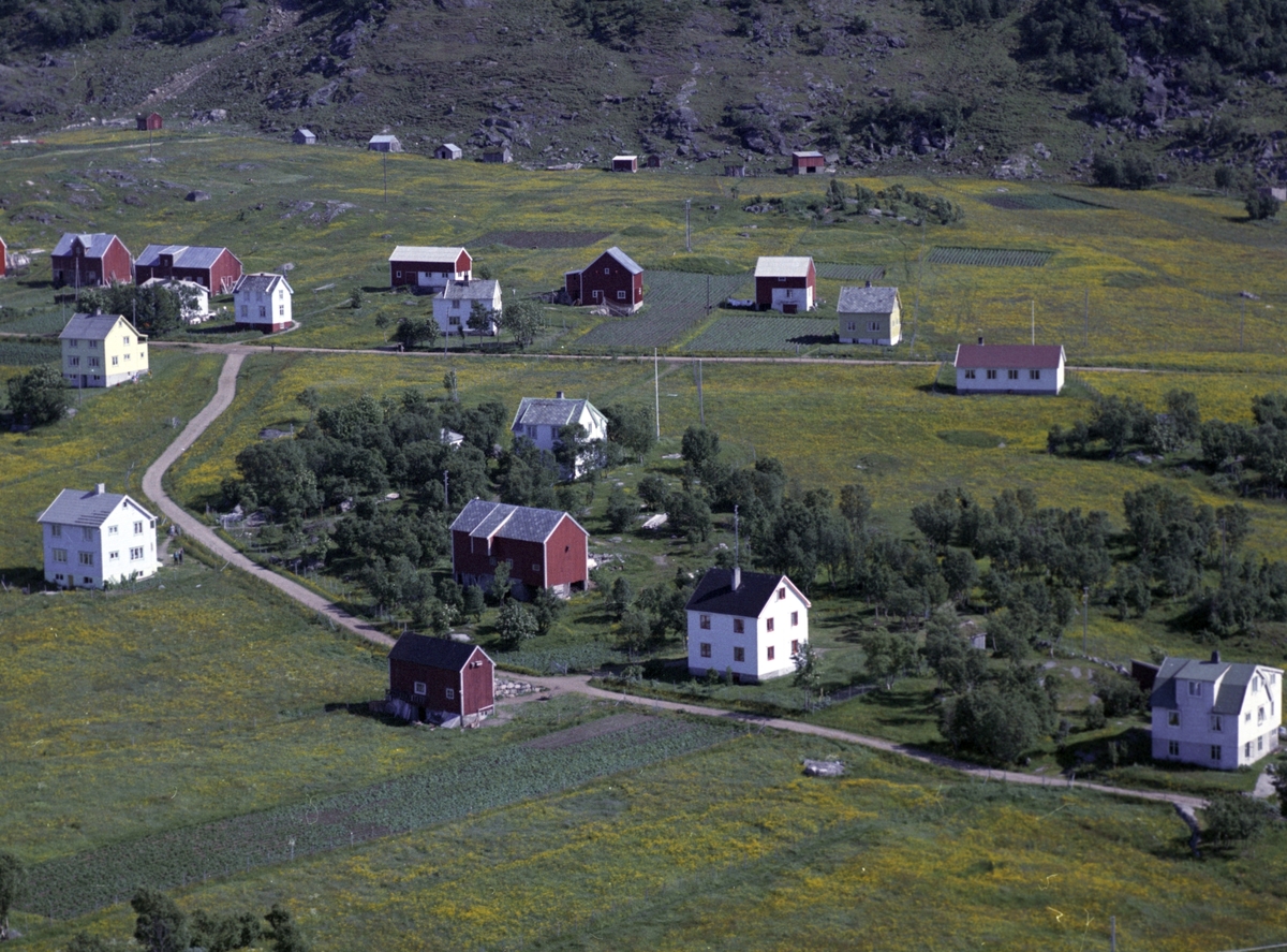 Flyfoto av bebyggelse på Grøtavær. Bedehus til høyre, sommerfjøser i bakgrunnen.