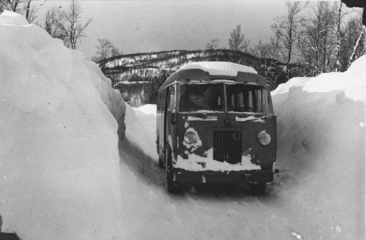 Buss på vinterføre, omgitt av høye brøytekanter.