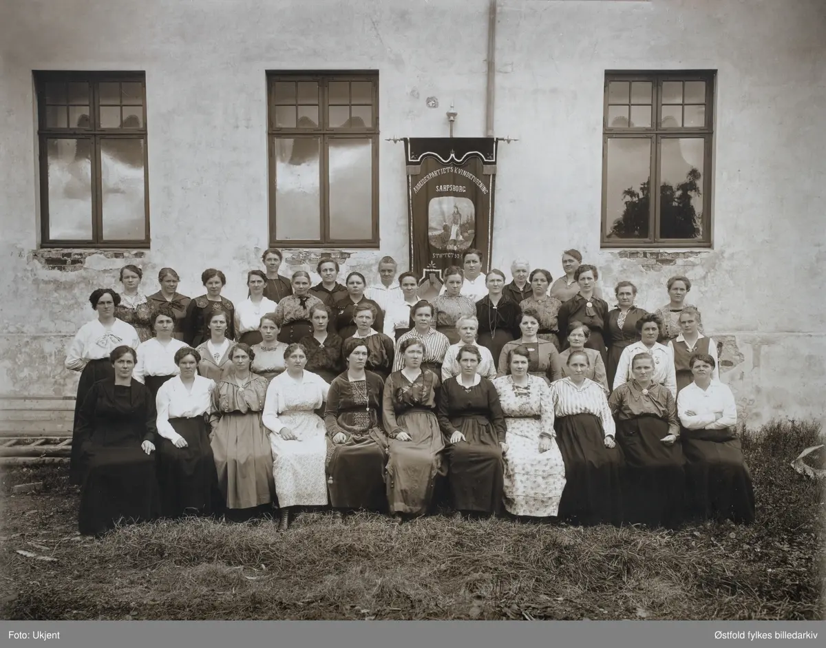 Arbeiderpartiets Kvinneforening i Sarpsborg, ca. 1918-1920.
Dato på fane (årstall ikke synlig)  - foreninga blei stifta i 9.2.1907. 
Fotografert utenfor det gamle Folkets Hus i St:Marie gate 38 Sarpsborg.

I andre rekke nummer 12 fra venstre, er Inga Torp (Kari Torp), som var gift med Oscar Torp, som også var sarping. 
I fjerde rekke fra venstre nr seks: Anna Enge, som var gift med Ludvig Enge, politiker og den første sosialist  fra Østfold på Stortinget. Blei seinere ordfører i Sarpsborg.

Marie Bergine Krogfos Johansen. (1867-1934)
 i tredje rekke nr 2 fra høyre. (Bestemor til Karin Haugen f. Johansen)
