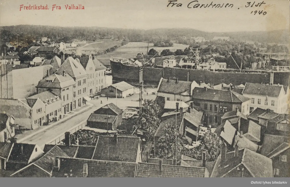 Oversiktsbilde fotografert fra Valhalla i Fredrikstad. Stor båt ligger ankret opp i elva. Postkort ca. 1905-10.

Vi ser fra Valhalla mot Glomma og Fredrikstad mekaniske verksted på Kråkerøy, nederst til høyre i bildet er dagens Holmen-område, det som før ble kalt Trosvikstranda eller bare Stranda. Den åpne plassen eller torvet er Gressvikbrygga, gata vi ser i forkant  som går på tvers av bildet er Storgata. Gata soom skrår til venstre opp i bildet er St. Hans gate.
(Aage Dedekam 2014) 

I kommentaren sies at vi ser dagens Holmenområde, det gjør vi ikke.  Det vi ser i forkant er husene langs Bakgaten (nå Farmannsgate).  Holmen er utenfor bildekanten til høyre.
(Gunnar Andreasen 2016).