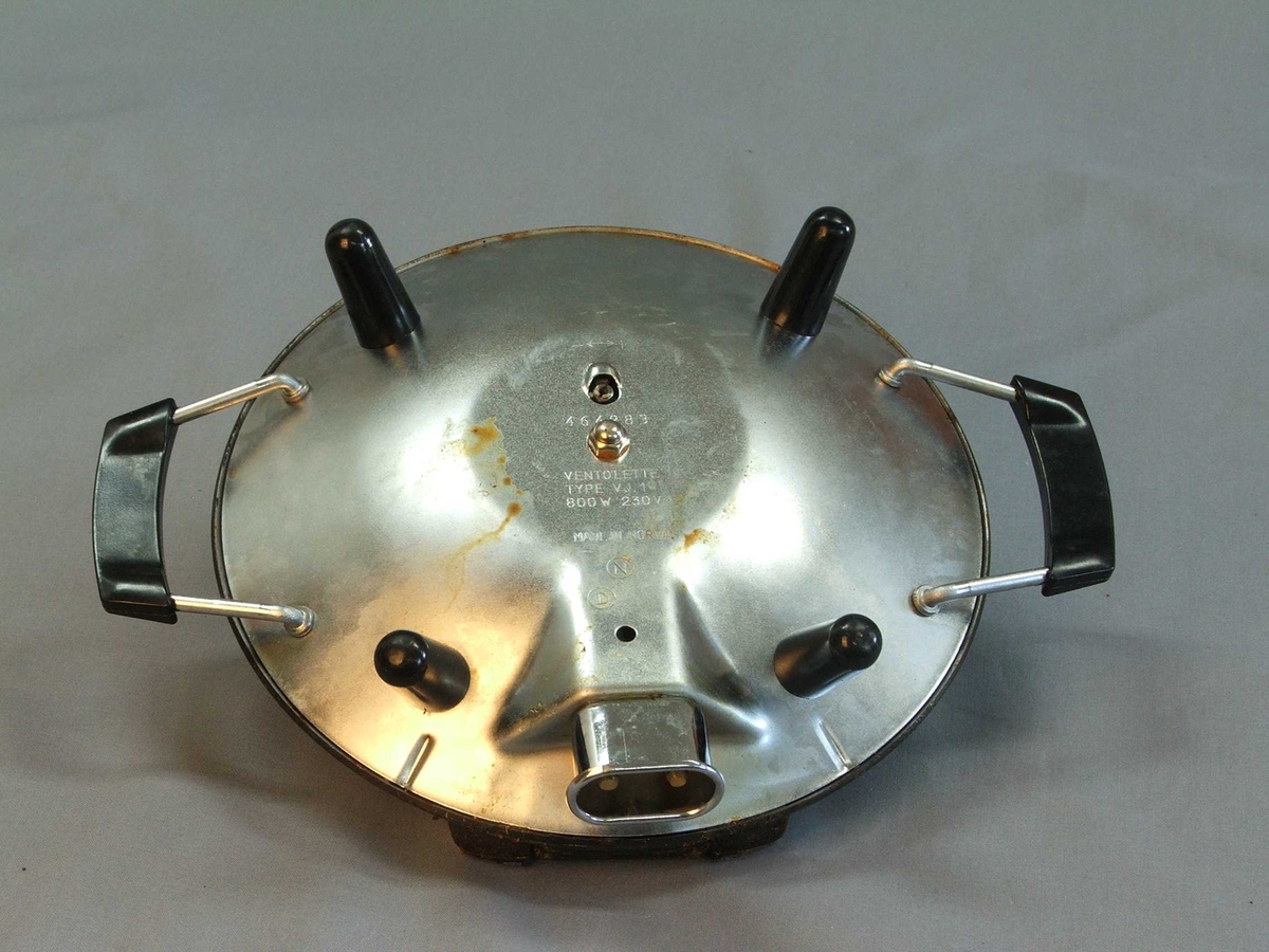 Eit vaffeljarn i original øsjke, isopor i øskja som jarnet står på. Det er ikkje ledning. Jarnet: Rund form. Loket opnast med handtak midt framme. Loket er hengsla fast til underdelen. Loket kan stå oppe av seg sjølv. Utsida av jarnet: oppå og under er det blankt metall, svart handtak på lok og to på kvar side av understellet. Inni er jarne svart, støypejarn? Vaffelhjarte-formar inni jarnet både på lok og botn = fem små hjarte som dannar ein sirkel. Fire svarte bein på undersida som jarnet står på.
Øskja er grøn med ein gul vaffel på oppsida og eit kvitt hjarte på sida. Øskja kan du opne framme. Den er kvit inni.