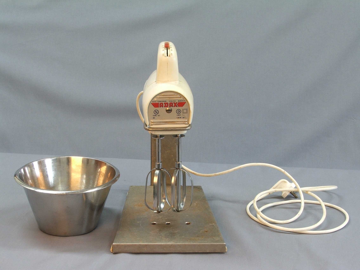 Miksmastar i fem delar: Stativ, bolle, maskin med leidning, to vispar. Stativet er av stål, her kan bollen stå oppå og maskinen stå ned i ei råme med vispane ned i bollen. Bollen er i rustfritt stål. Maskinen er tung, handtak øvst, knapp med fire trinn også øvst. Uttak til vispar under. Vispar samansett av to ovalar med stålband.