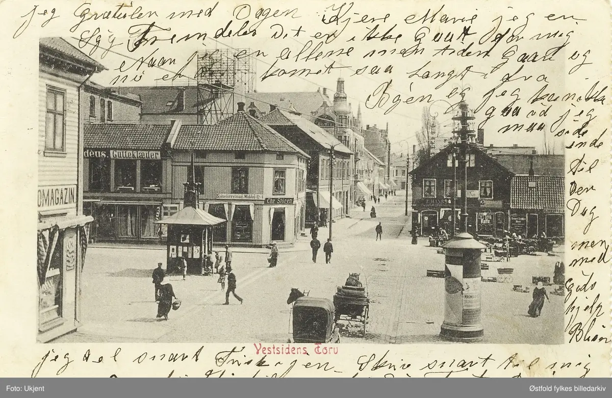 Vestsiden Torv i Fredrikstad, fra prospektkort med uleselig poststempel. Dateres til 1904-1906 ca fordi hjørnebygningen til venstre brant under bybrannen i 1908 (der lå Raade Skomagazin). Fra 1906 var det tillatt å skrive på bildeside av postkortet.

Butikker av forskjellige typer omringer torget, mennesker og hest med vogn er i ferd med å krysse. "Gutteklæder" står det på et butikkskilt over en av butikkene som vender ut mot torget.