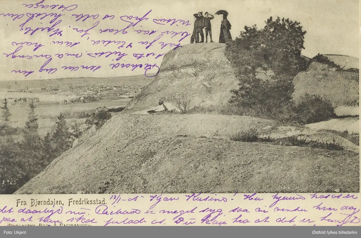 Barbertoppen mellom Bjørndalen og Oredalen i Fredrikstad,  prospektkort ca. 1905.

Bjørndalen er en dalsenkning mellom Kniplefjellet/Oredalsåsen i vest og parallell åsrygg fra Bratlifjellet til henimot Høyfjellet i øst.

Flere mennesker står på en topp og skuer utover. Damen i følget bærer en parasoll.
Boligstrøket Bjørndalen, som sannsynligvis ligger rett bak, er en forlengelse av bebyggelsen på Trara og inngangspartiet til turterrenget i Fredrikstadmarka.

Det vi ser her er Barbertoppen, et fjellparti mellom Bjørndalen og Oredalen.  Her er det en inskripsjon som general Cicignon lot hugge inn i fjellet, som begynner slik: "Belvedere per el mare" (Vakker utsikt over havet), og det antas at "Barber" er en folkelig forvanskning av "Belvedere".  I de første tiår av det 20 århundre samlet mange mennesker seg her til påskevake for å bivåne soloppgangen på påskemorgen.  Kilde:  Fredrikstad Byleksikon