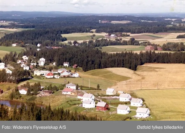 Skråfoto av boligfeltet Mjørudhaugen ved Skriken i Rakkestad, 11. sept. 1963. 
Rakkestadelva renner forbi i forgrunnen.