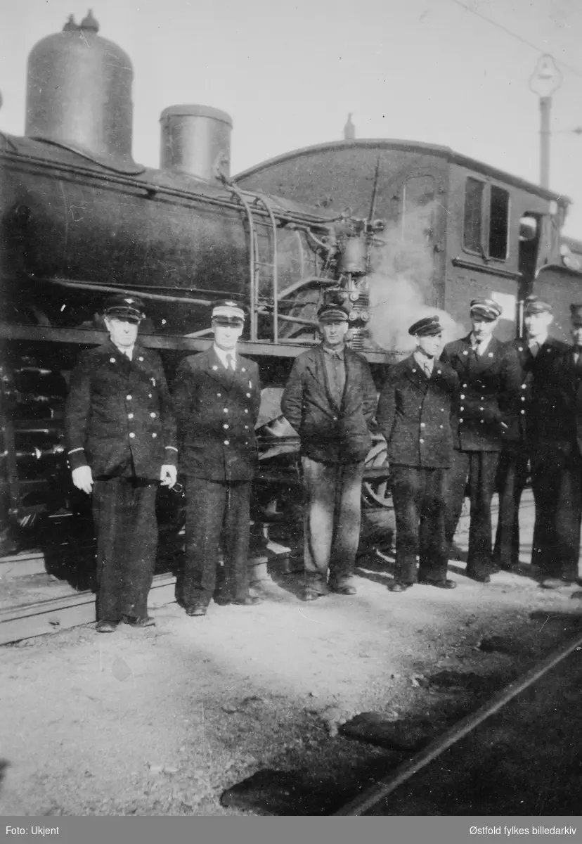 Damplokomotiv på Fredrikstad jernbanestasjon ca. 1940. Fra v.: A. B. Lystad, stasjonsmester R. Dahl. Øvrige ukjente.