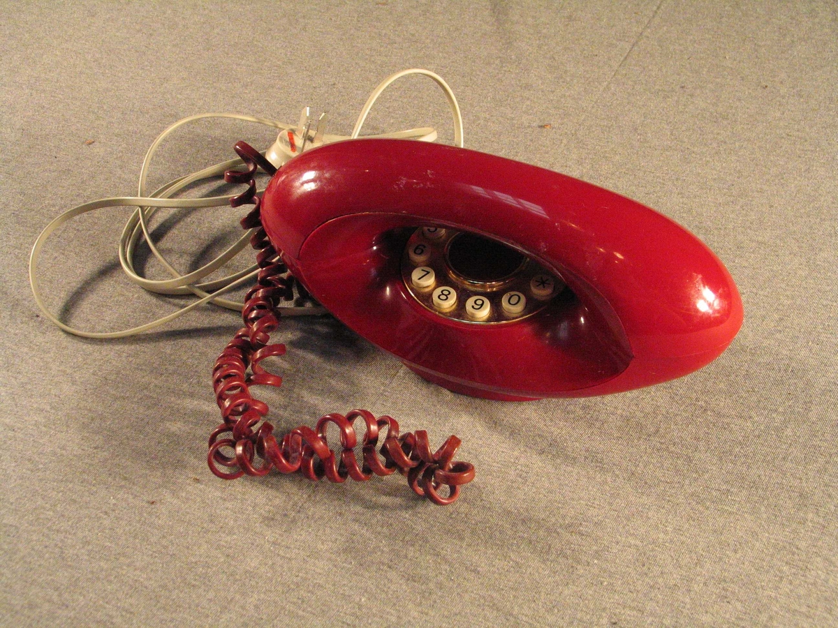 Båtforma haldar med tastatur. Står på ein liten oval stett. Rund gullforgyllt talskive med firkant- og stjernetast.Når røyret er lagt på har apparatet ein oval profil med opning i midten. Ledning med stikkontakt.
Sjå referansar/andre oppl.