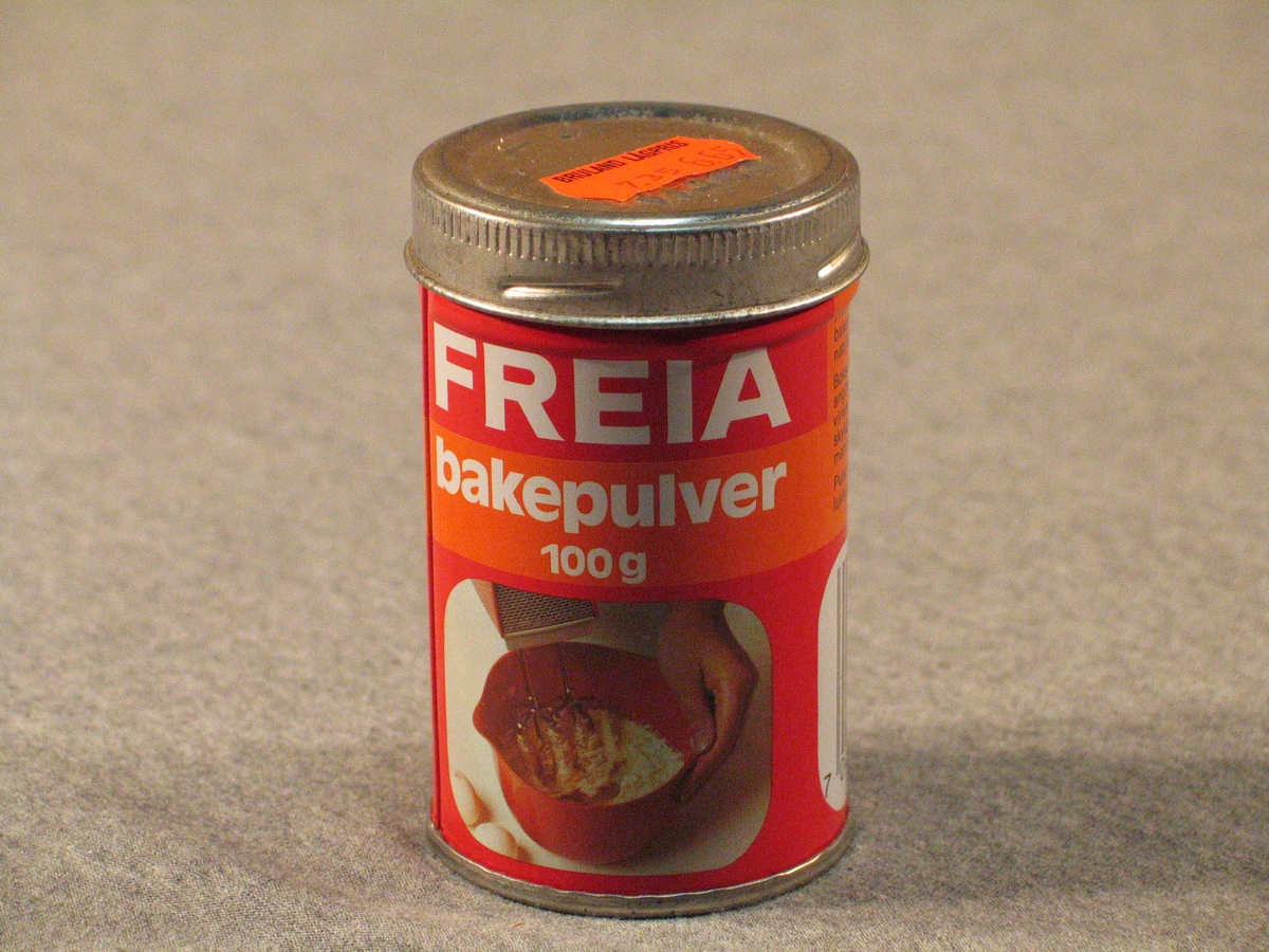 Rett blekkboks med skrulôk. Kring halvfull med bakepulver.
På lôket er orange prislapp frå Bruland Lågpris "7,35  6,65". Truleg betyr det  "vanleg pris" og "vår pris". det er strekkode på boksen, men butikken har truleg ikkje hatt avlesingsutstyr