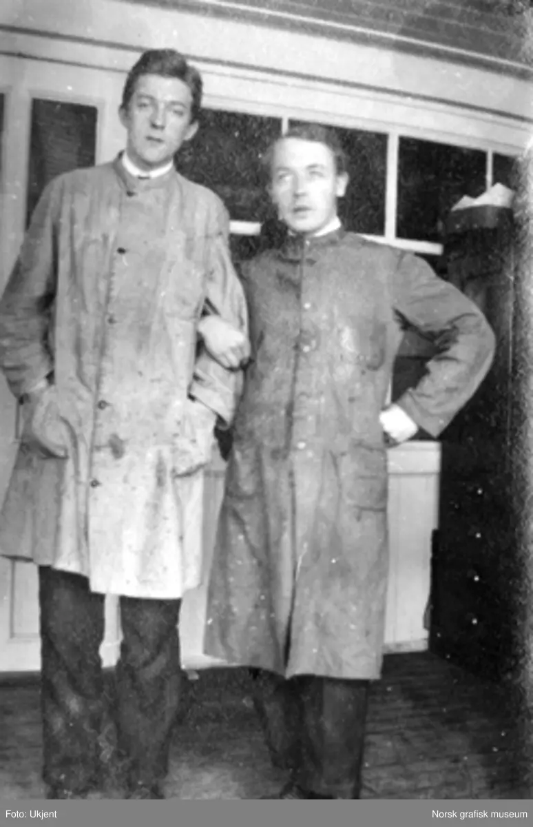 To menn i arbeidsfrakk poserer for fotografen. Dreyers Reproduktionsanstalt. F.v. Trygve Berge, Jakob Roalsvig.

Albumtekst:
"Hurra for den lille forskjel" (henspeiler nok på høydeforskjellen mellom de to mennene!)