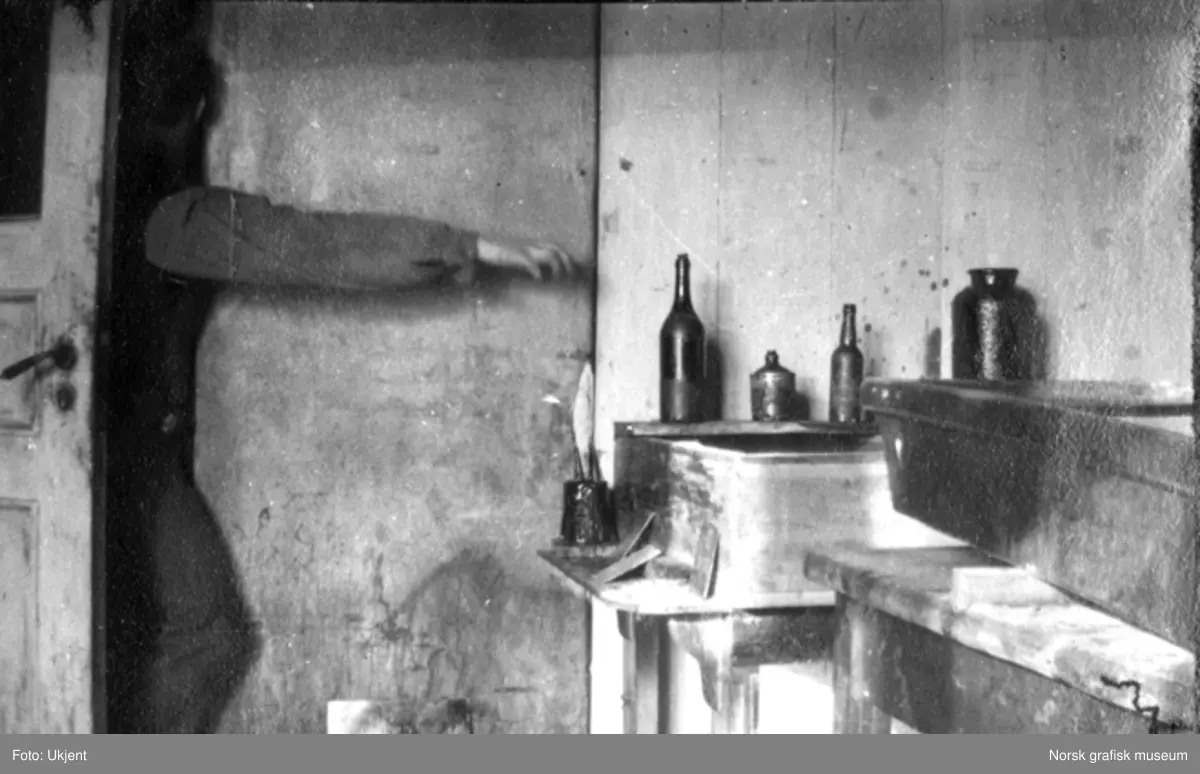 En arm strekker seg inn en dør, mot noen flasker på en hylle.

Albumtekst:
"Spritmysteriet. Til den som kan fakke sprittyvene utloves i tusenvis av kroner. Revolver(?Selius?)"
