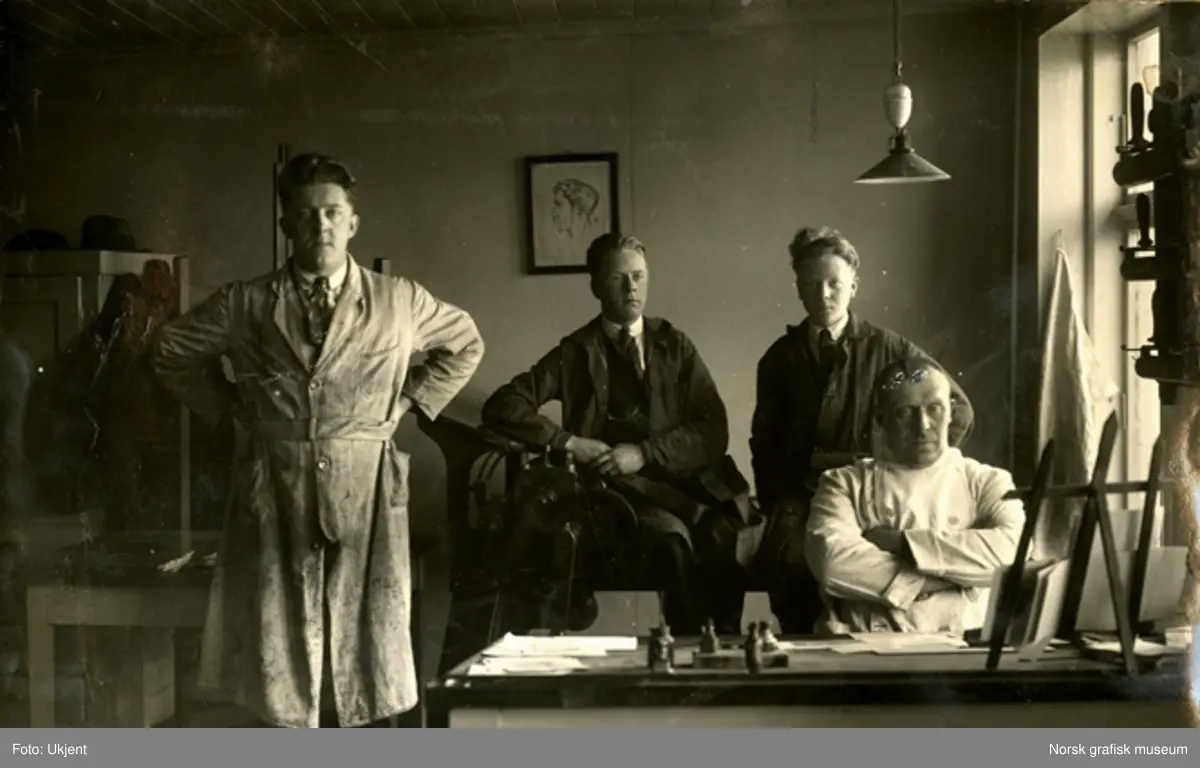 Fire menn i arbeidstøy ved en arbeidspult på Dreyers Reproduktionsanstalt. F.v. Trygve Berge, Arne Larsen, Ole Birkeland og Kurt Allendorf. 
Albumtekst: "15-3-30. FAUST" samt navnene på de avbildede.