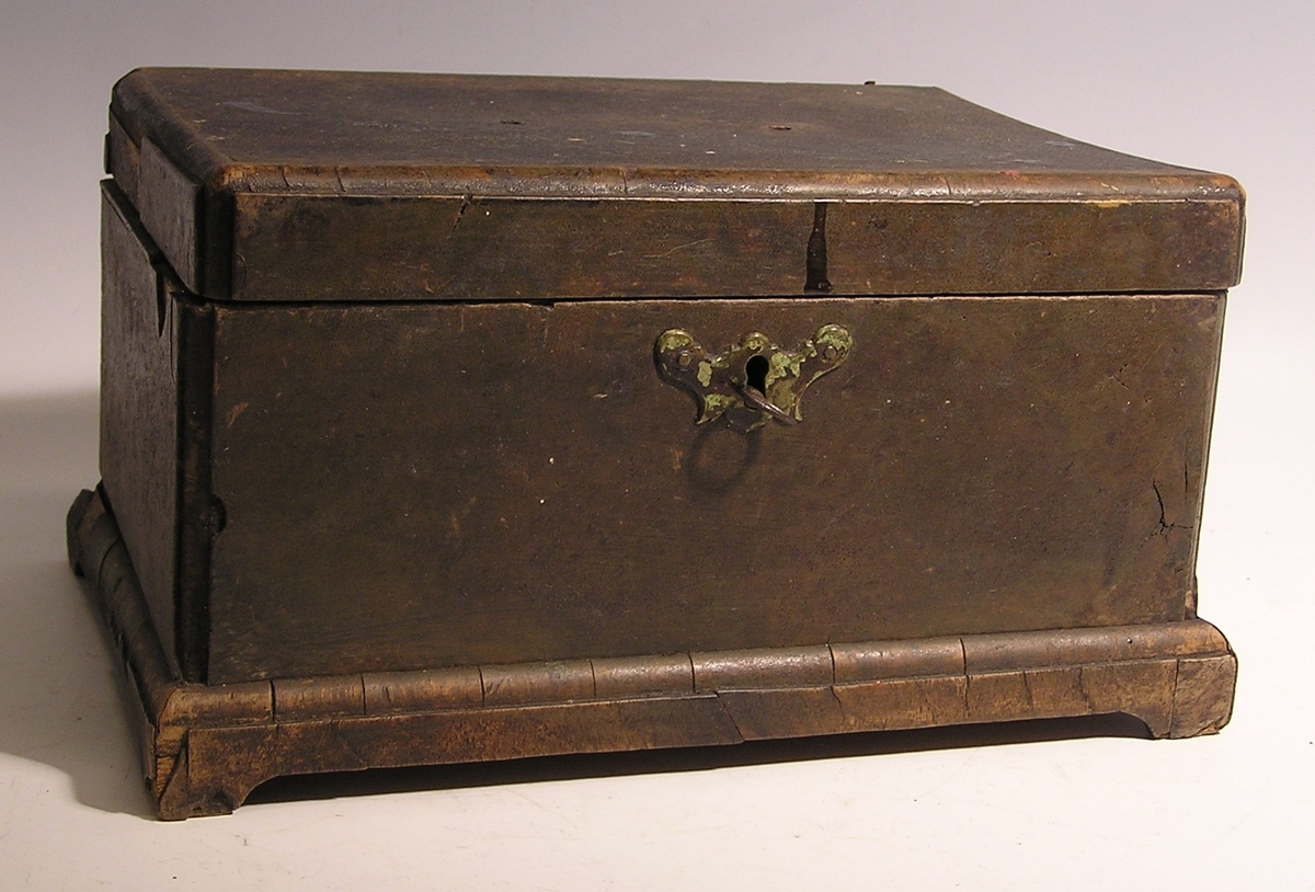 Rektangulær skrin med lokk og nøkkelhull. Liten nøkkel ligger i hullet.  Fotliste. Rommet er inndelt og inneholder små medisinflasker, krem og hodetabletter.
Ligner liten skipskiste.