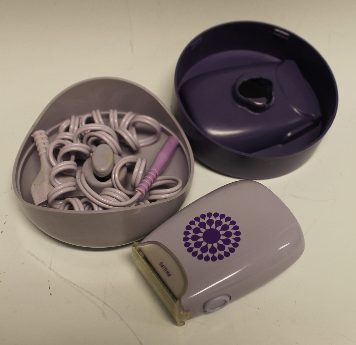 Bargbermaskin med ledning og etui. Etui er i tre deler som passer inni hverandre. Ledning ligger nederst i en hylle for seg.