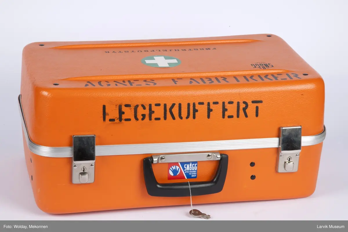 Legekoffert med diverse utstyr som bandasje, plaster, gasbind, bomuld, diverse sakser, sprøyter etc., samt liste over innhold.

Førstehjelpskoffert koffert til bruk for lege som kommer tilstede ved ulykker i bedrift.

2 nøkler henger fast i håndtaket.