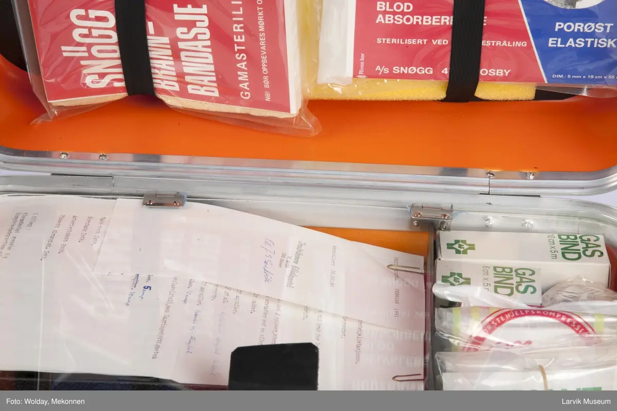 Legekoffert med diverse utstyr som bandasje, plaster, gasbind, bomuld, diverse sakser, sprøyter etc., samt liste over innhold.

Førstehjelpskoffert koffert til bruk for lege som kommer tilstede ved ulykker i bedrift.

2 nøkler henger fast i håndtaket.