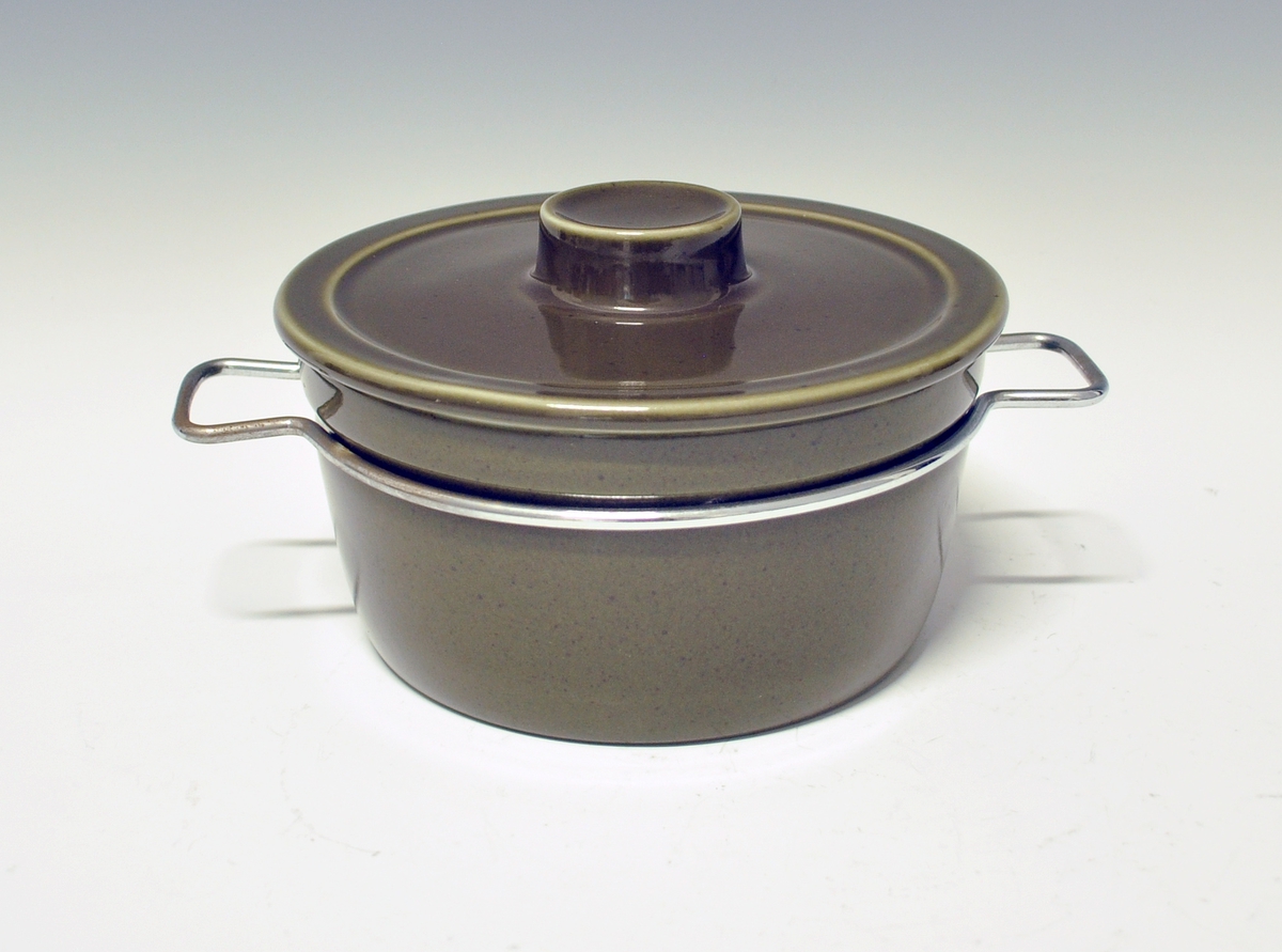 Gryte med lokk av porselen, ildfast gods. Mørkegrønn glasur. Metallhanker.
Modell 2376 Askeladden av Eystein Sandnes, i produksjon fra 1964.