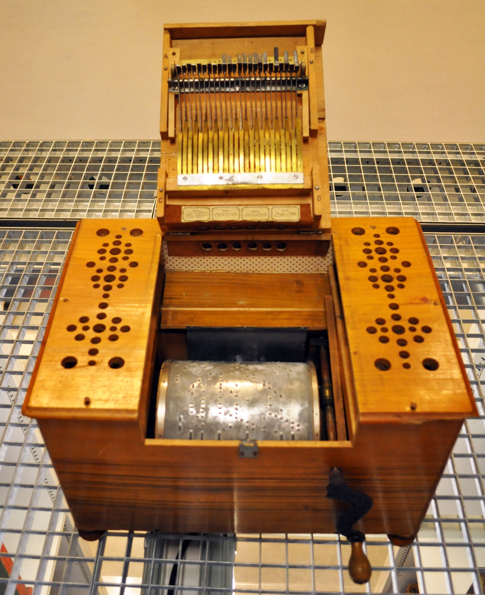 Lirekasse med sveiv - navneskilt foran "CLARIOFLUTE". Tilhørende tinn-plater med musikk på, se TGM.2011:0313.