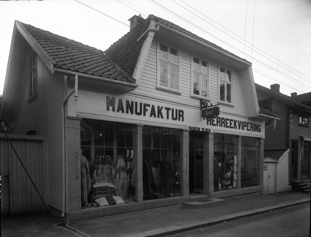 Markus Olsens forretning i Storgata i Langesund. Storgata 3 eller 5. Huset er senere bygd om. De slo sammen det hvite huset og det brune ved siden av. I det brune ble det en avdeling med gardiner og stoffer etc, mens det var klær i det hvite. De bygde en liten trapp (2-3 trinn) mellom de to avdelingene.