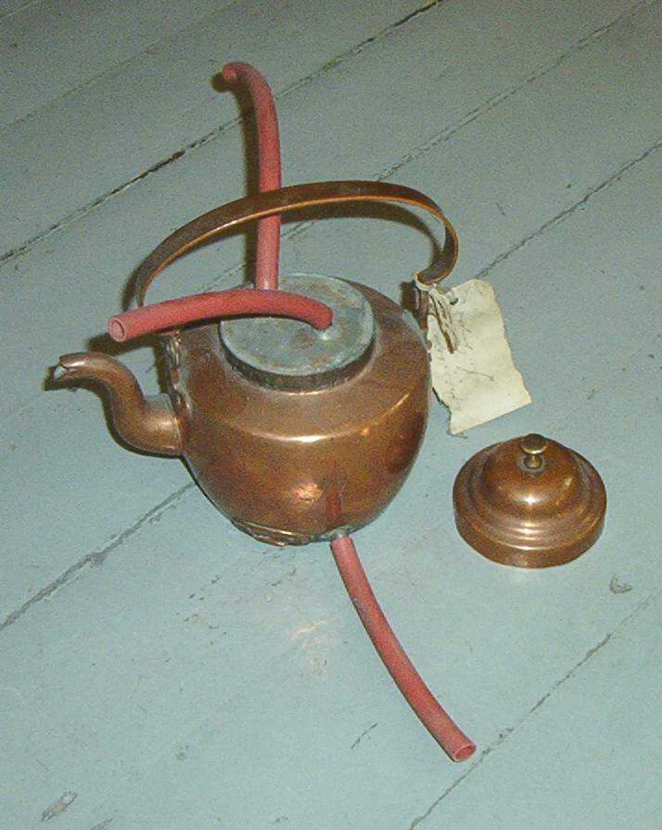 Kaffekjele av kobber.  En gummislange er festet til et hull i bunnen.  To gummislanger er festet i toppen av kjelen.