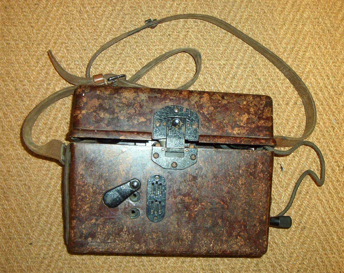Felttelefon. Feldfernsprecher 33, FF33, tyskprodusert. Serienummer 74058.  Produksjonsår 1941. Telefonen er innebygd i bakelittkasse med bæresele. Hvit kodelapp montert på lokket. Det tyske alfabet står skrevet på lokket.