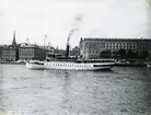 Skärgårdsångaren EXPRESS på Stockholms ström med Skeppsbron och Kungliga slottet i bakgrunden.