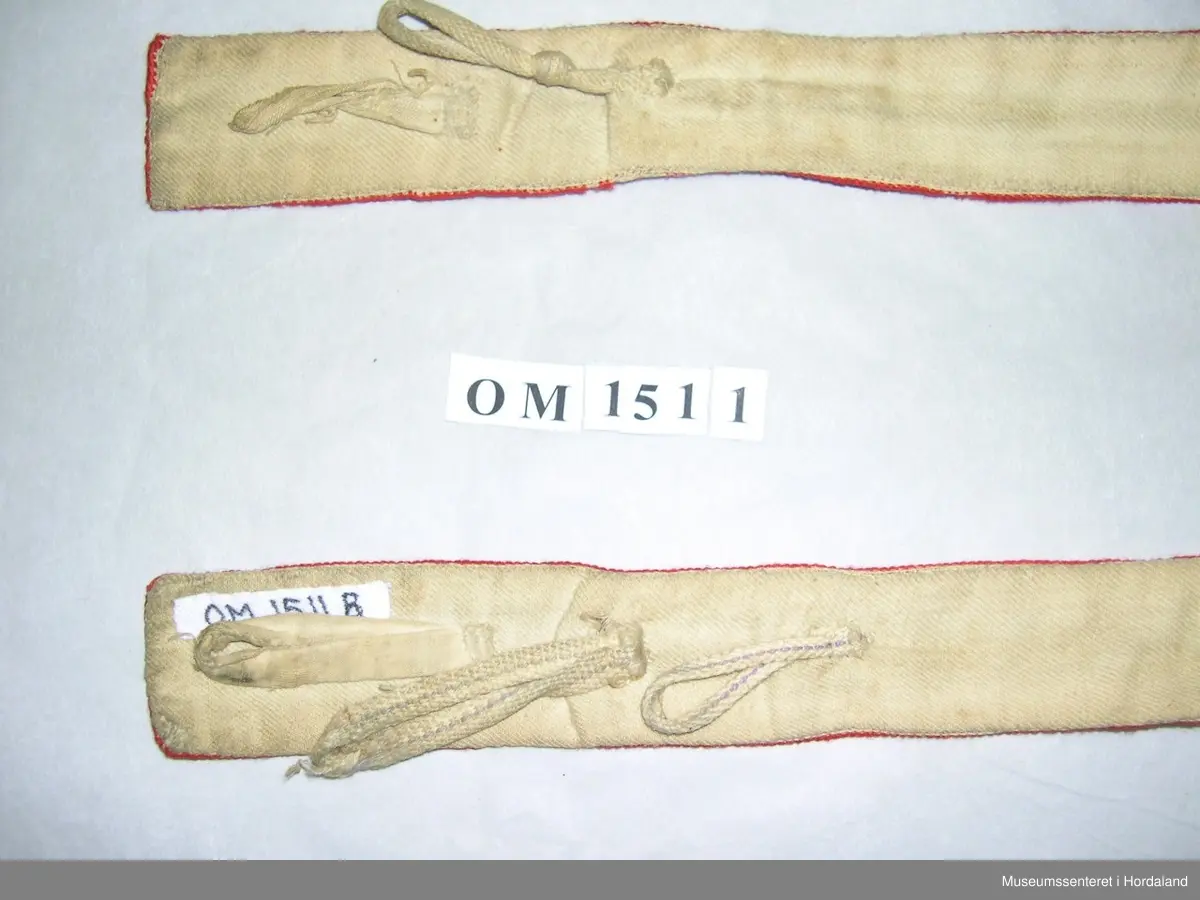 Eit par mannsseler brodert med halve krossting. Hovudfarge er raud, med mønsterdekor i lilla, grønt og gult. Her er òg felt som ikkje er sydd slik at den ubleika strameifargen under kjem fram. Selane har hemper på baksida til festing på buksa. Litt slitt.