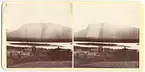 Stereoskopbilder med vy över Lappländskt landskap. Några byggnader i förgrunden, troligen Prästgården. I bakgrunden Kamajokkforsens vatten och Krutholmen. I fonden berget Nammatj.