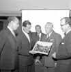 Bertil Thorburn förevisar ett fotografi som visar Götaplatsen i Göteborg för fyra intresserade män