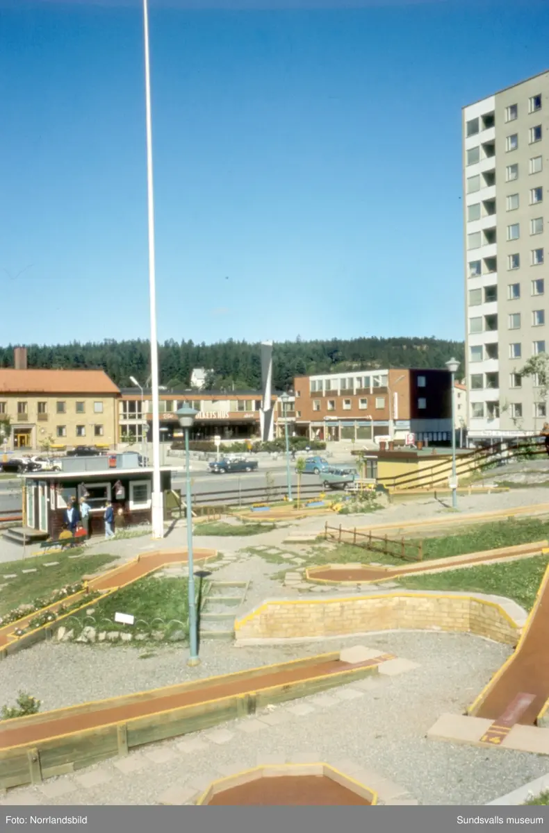 Centrala Skönsberg med höghuset, Folkets hus med skulpturen Spiral reflex, minigolfbana och lekpark.