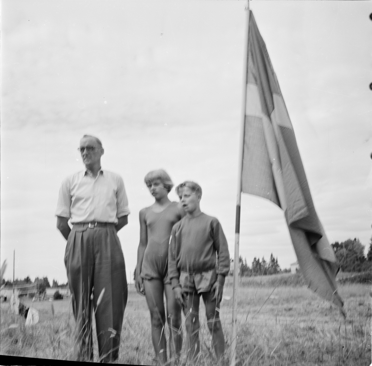 Man och barn vid flagga, Uppland 1955