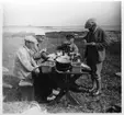 'Akka-expeditionen sommaren 1931: ::  :: 4 st män äter frukost vid dukat bord på stranden. Vy mot havet. Leonard Axel Jägerskiöld sittande vid kortsidan av bordet. Kläder. Klädsel. ::  :: Ingår i serie med fotonr. 2182-2234.'