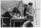 'Kattegattexpeditionen 1933: ::  :: ''Skandia'' i Glommen. 6 st personer vid dukat bord på båtens däck, Hugo Oldeberg (till vänster), knappt synligt huvud, Leonard Axel Jägerskiöld (sittande vid kortsidan av bordet), Harald Alander, Anders Eliasson och Sune Swärd (längst till höger). ::  :: Ingår i serie med fotonr. 2804-2826.'