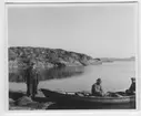 2 män i eka, Leonard Axel  Jägerskiöld stående på stranden. Vy med berg.