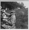 'Biologiska Föreningens utfärd till Oset och Kvismaren. ::  :: Leonard Axel Jägerskiöld (lyfter sitt glas) m.fl. sittandes på en gräsluttning med glas och tallrik i händerna. Fotograferad från sidan från nära avstånd. Kläder. Klädsel. ::  :: Ingår i serie med fotonr. 4386:1-18.'