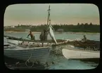 'I förgrunden båtar, ekor med fångstnät emellan, 4 män i båtarna i arbete med att ta upp tonfick. Text på glaset: ''Tuna fishing at Hubbards N.S. Landing fish into boat fron Spiller Ne''. I bakgrunden syns strand och hus. ::  :: Ingår i serie med fotonr. 5205:1-20. Se även hela fotonr. 5202-5218 med bilder från Frits Johansen.'