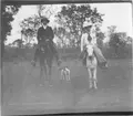 'Diverse fotografier från bl.a. dåvarande Nordrhodesia, nu Zambia, tagna av Konsul Magnus Leijer. ::  :: En man och en kvinna sittandes på en varsin häst, emellan dem står en hund. I bakgrunden är träd synliga.'