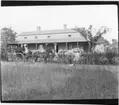 'Diverse fotografier från bl.a. dåvarande Nordrhodesia, nu Zambia, tagna av Konsul Magnus Leijer. ::  :: En man och en kvinna med barn sittandes i en vagn dragen av en häst framför en större bostadsbyggnad. Framför ekipaget är en hund synlig.'