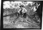 'Diverse fotografier från bl.a. dåvarande Nordrhodesia, nu Zambia, tagna av Konsul Magnus Leijer. ::  :: 1 st man sittande i jakrutrustning med en fälld leopard vid fötterna, ytterligare 2 st män är synliga.'