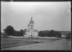 'Vy med 1 kyrka, människor gående, stående framför och till höger skymtar en droska, ekipage, häst och vagn. Samma kyrka som fotonr. 5282:11. ::  :: Ingår i serie med fotonr. 5282:1-15. Se även fotonr. 5269-5292 med bilder från Stuxbergs resa till Kaukasien.'