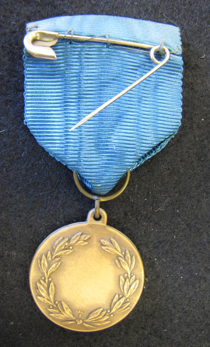 Medalj med sidenband i blått.

På åtsidan ligger en man sikande med gevär. På frånsidan en lagerkrans.

Medaljen ingår i en samling märken och medaljer sittande på en tavla med märken, framförallt skyttemärken.

Karl-Fredrik Nyström var aktiv fritidsskytt och var en av de drivande för att starta Vänersborgs skytteklubb.