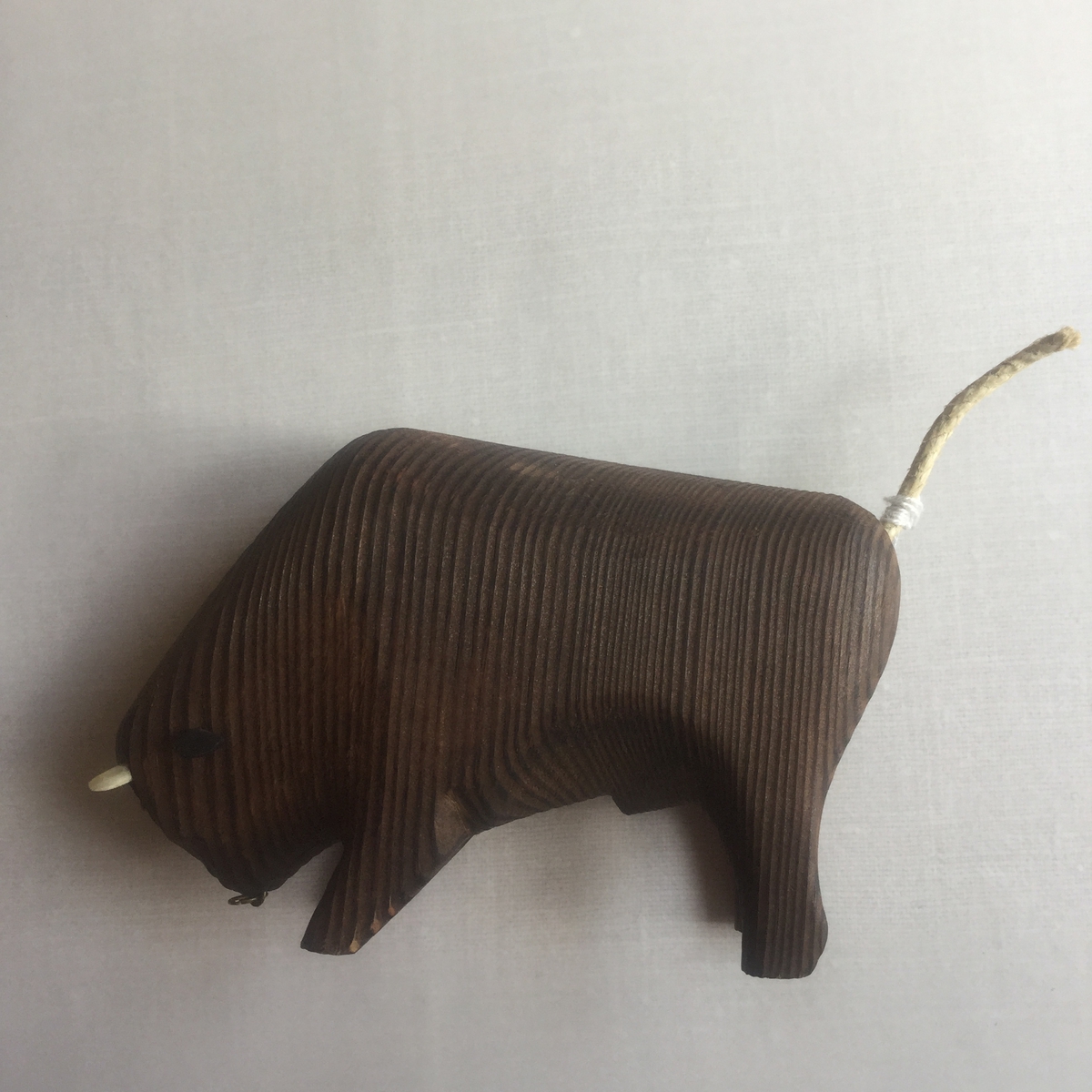 Buffel i trä med nosring i metall. Svans av snöre, öron i läder.