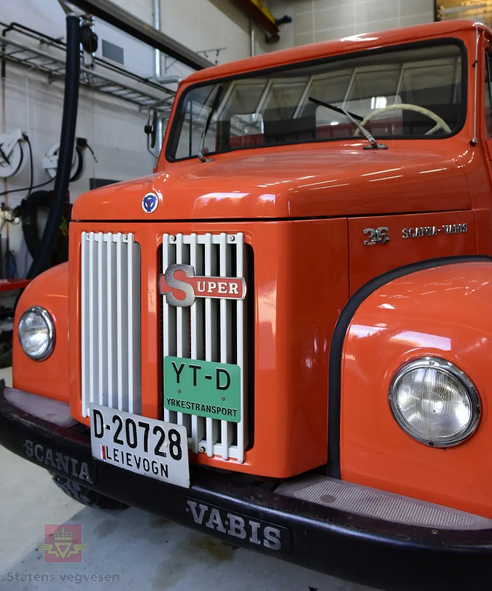 Lastebil på 6 hjul, (to akslet) med bakhjuls drift. Akselavstand 4,2 meter.  I hovedsak oransje. Motoren er en turbomatet 4-sylindret dieselmotor av typen Scania-Vabis DS5, den yter 120 hestekrefter og har et sylindervolum på 5193 kubikkcentimeter. Girkassen er en manuell 5-trinns synkronisert utgave, høy- og lavgir i bakakslingen (two-speed) gir tilsammen 10 gir pluss revers. Bremsene er drevet av trykkluft. Bilen har lasteplan med karmer og et ekstra sett karmer på toppen. Bilen har 3-veis hydraulisk tipp fra Thanstrøm i Halden. Svart interiør, lakkert grå innvendig. Egenvekten er ca. 5,1 tonn, lasteevne ca. 5,825 tonn. Totalvekt 11 tonn.
Farge: paprika rød.