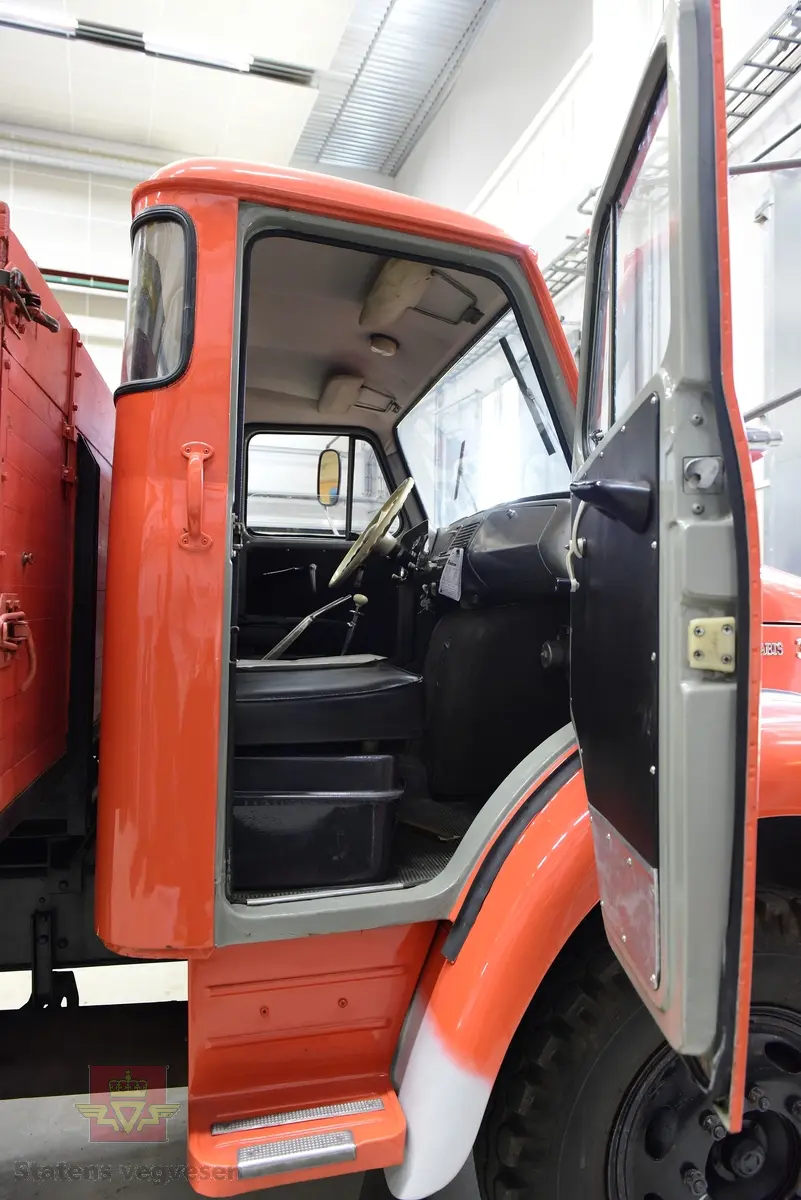 Lastebil på 6 hjul, (to akslet) med bakhjuls drift. Akselavstand 4,2 meter.  I hovedsak oransje. Motoren er en turbomatet 4-sylindret dieselmotor av typen Scania-Vabis DS5, den yter 120 hestekrefter og har et sylindervolum på 5193 kubikkcentimeter. Girkassen er en manuell 5-trinns synkronisert utgave, høy- og lavgir i bakakslingen (two-speed) gir tilsammen 10 gir pluss revers. Bremsene er drevet av trykkluft. Bilen har lasteplan med karmer og et ekstra sett karmer på toppen. Bilen har 3-veis hydraulisk tipp fra Thanstrøm i Halden. Svart interiør, lakkert grå innvendig. Egenvekten er ca. 5,1 tonn, lasteevne ca. 5,825 tonn. Totalvekt 11 tonn.
Farge: paprika rød.