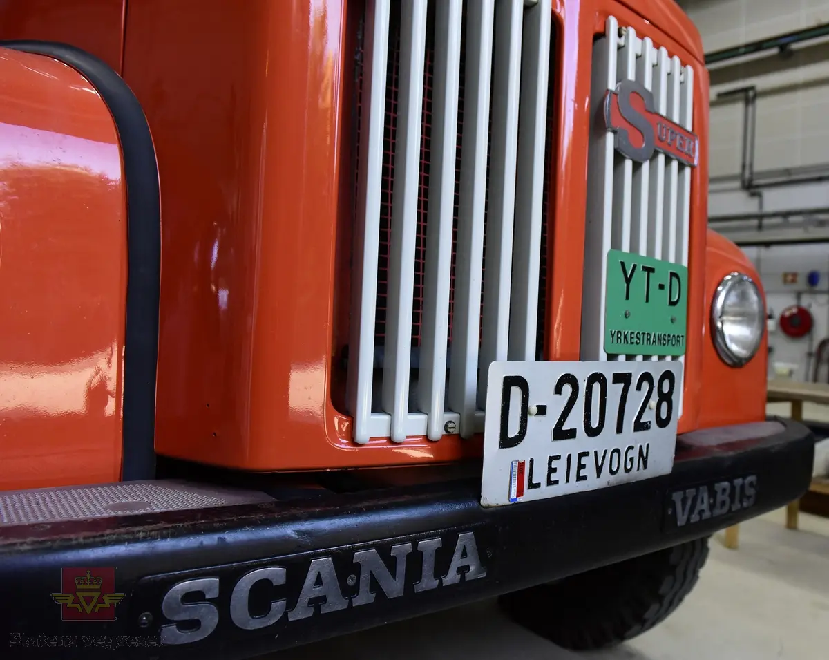 Lastebil på 6 hjul, (to akslet) med bakhjuls drift. Akselavstand 4,2 meter.  I hovedsak oransje. Motoren er en turbomatet 4-sylindret dieselmotor av typen Scania-Vabis DS5, den yter 120 hestekrefter og har et sylindervolum på 5193 kubikkcentimeter. Girkassen er en manuell 5-trinns synkronisert utgave, høy- og lavgir i bakakslingen (two-speed) gir tilsammen 10 gir pluss revers. Bremsene er drevet av trykkluft. Bilen har lasteplan med karmer og et ekstra sett karmer på toppen. Bilen har 3-veis hydraulisk tipp fra Thanstrøm i Halden. Svart interiør, lakkert grå innvendig. Egenvekten er ca. 5,1 tonn, lasteevne ca. 5,825 tonn. Totalvekt 11 tonn.
Farge: paprika rød.