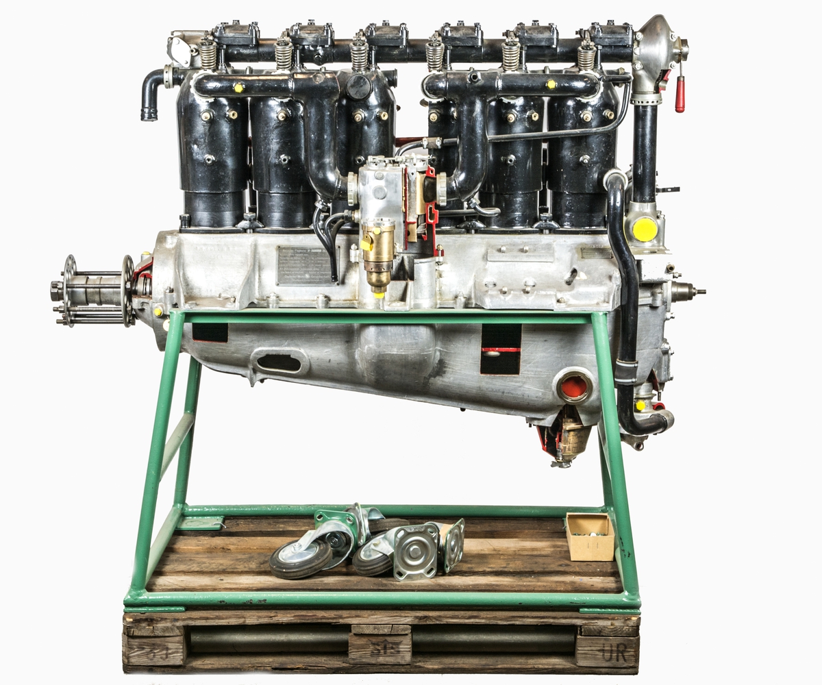 Flygmotor Mercedes 120. Motorn försedd med 1 magnet (trasig) samt dubbelförgasare. Motorn delvis uppskuren. Motorn placerad i bock med hjul. För flygplan Sk 5 och flygplan Sk 1.