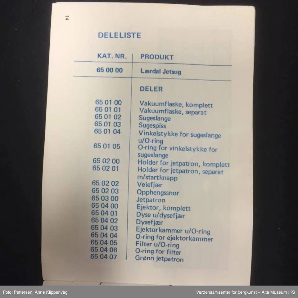 A. Sylinderformet plastapparat med tilfestet gummislange og gjennomsiktig plasttut.  Inneholder en driftspatron fylt med ufarlig gass.
B Rektangulært hefte, bruksanvisning.