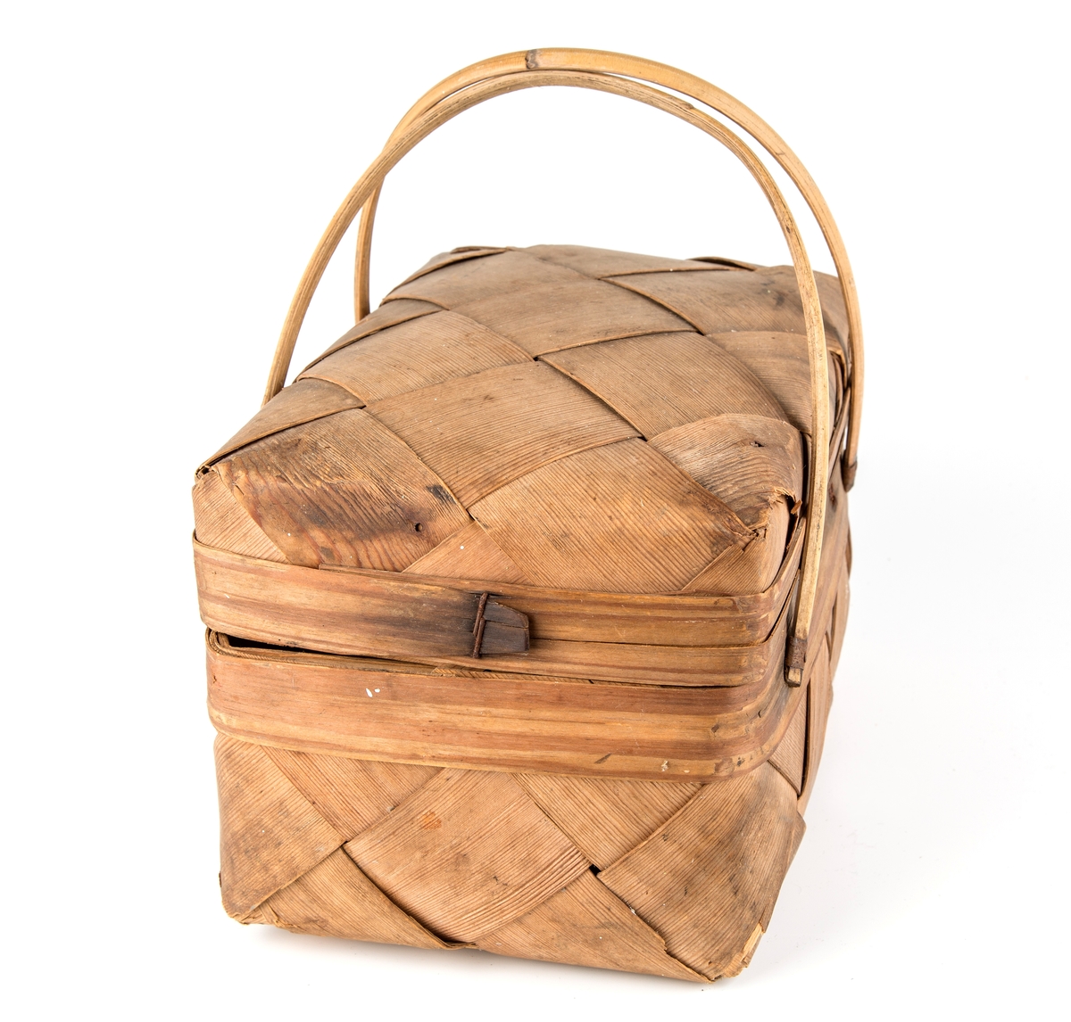 Rektangulær kurv, skråflettet av brede spon. Hengslet lokk, 2 hanker.